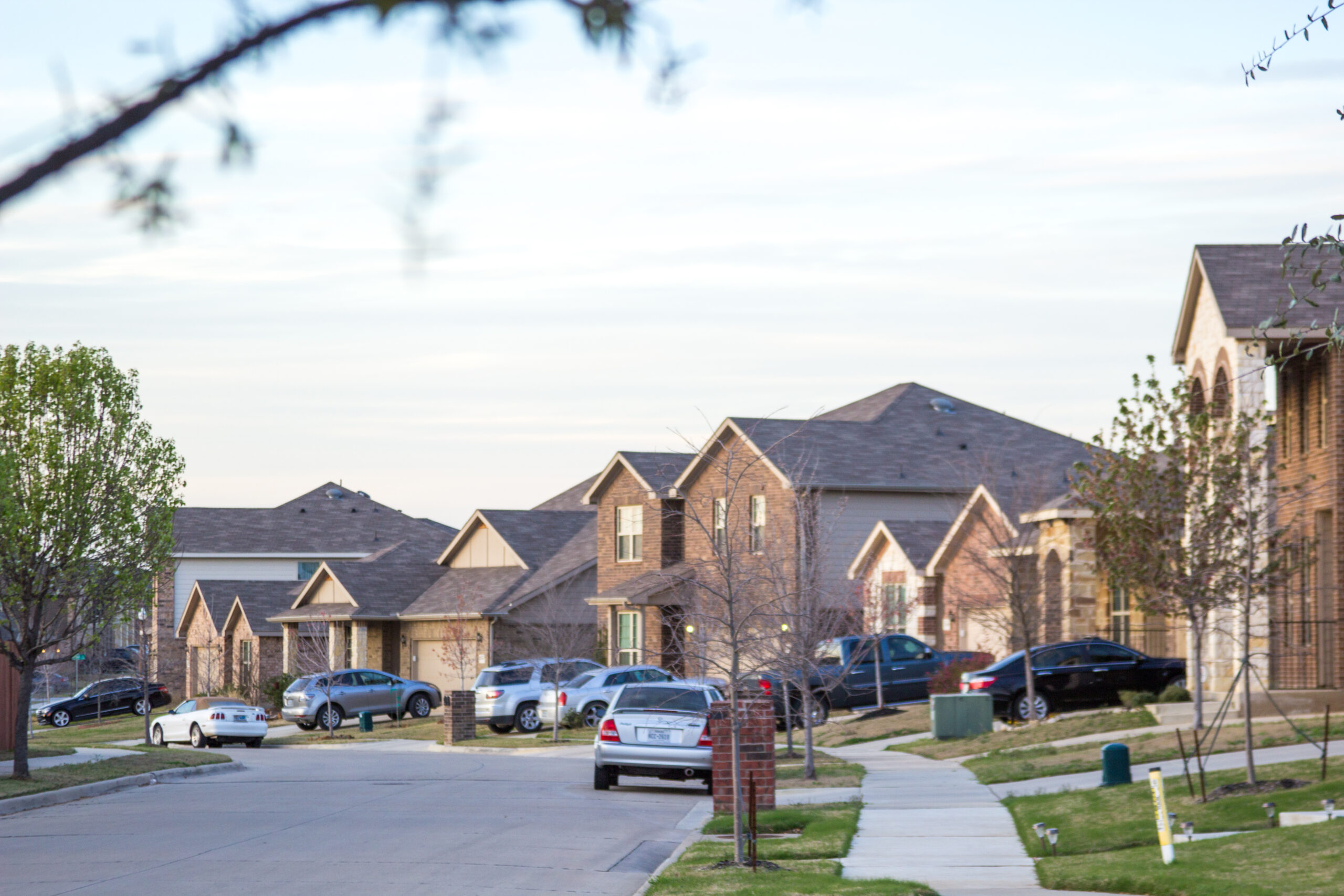 Quiet suburban street lined with single family homes and parked cars
